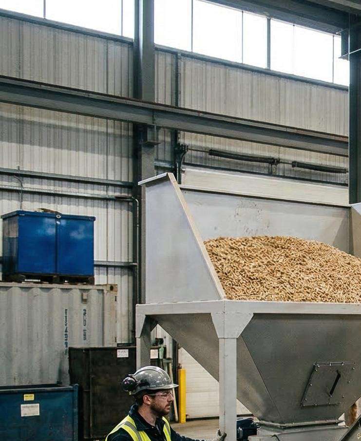 Worker loading biomass fuel into a hopper